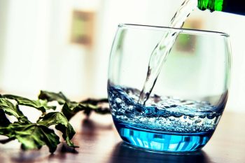 Минеральная вода наливать в стакан на столе